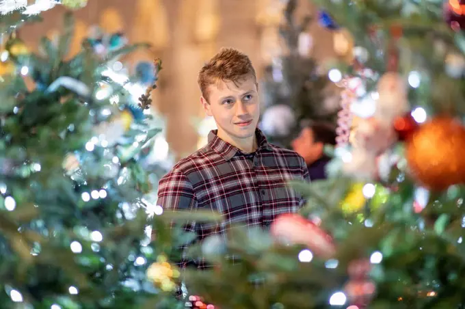 Young man looking at illuminated Christmas tree and lights in city