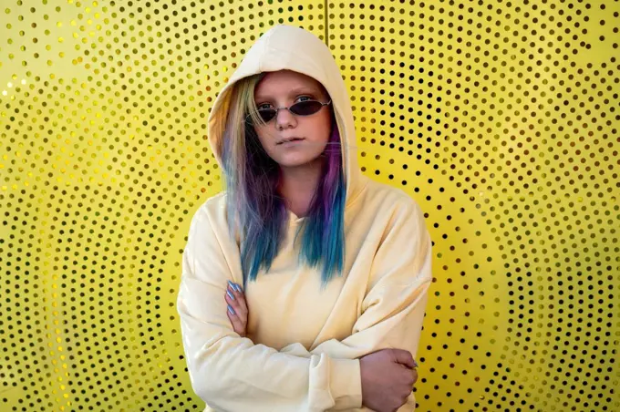 Portrait of young woman with dyed hair in front of yellow wall