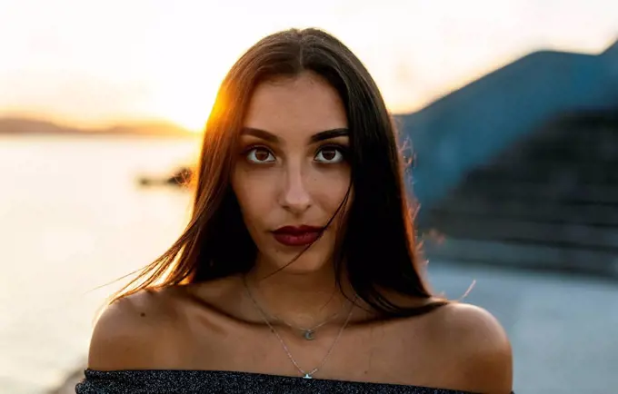 Beautiful woman standing at promenade during sunset