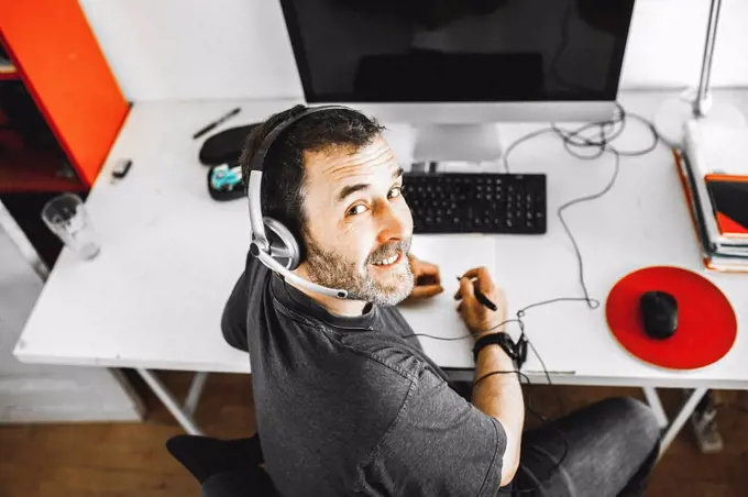 Man sitting on desk with headset working at home