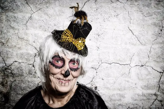 Portrait of senior woman with sugar skull make-up and fancy hat