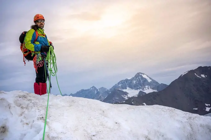 Mature man holding ropes while standing on snowcapped mountain against sky, Stelvio National Park, Italy