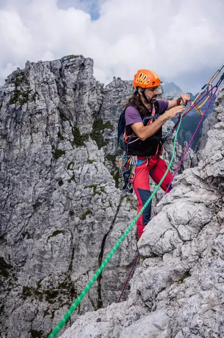 Mature man with ropes standing on mountain, European Alps, Lecco, Italy