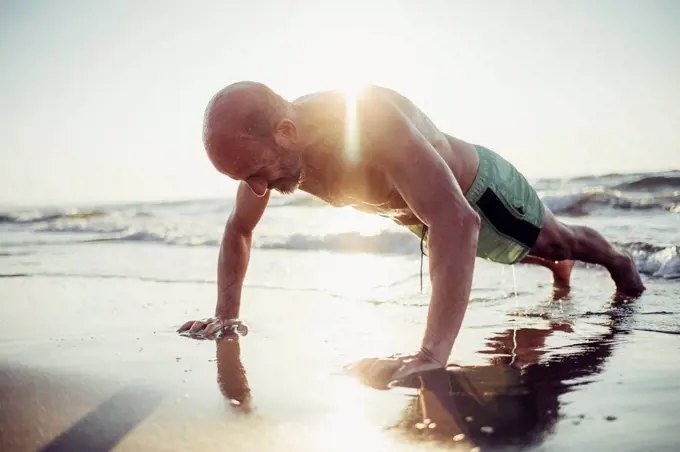 Senior man exercising at beach during sunset