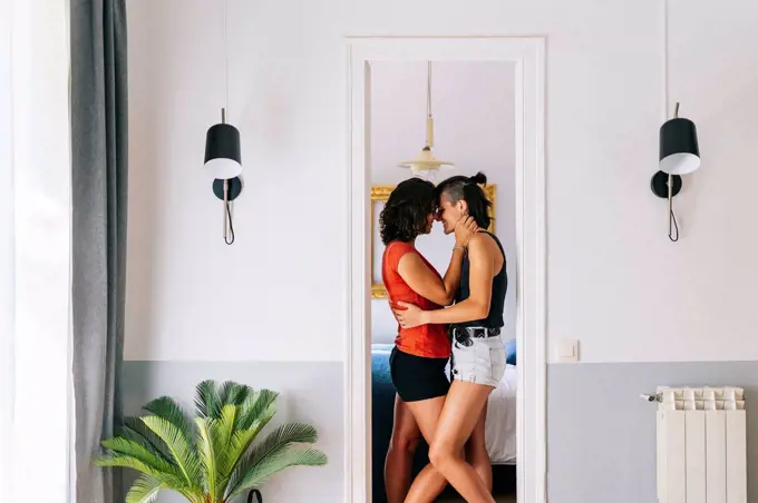 Female friends rubbing nose to each other while standing at doorway