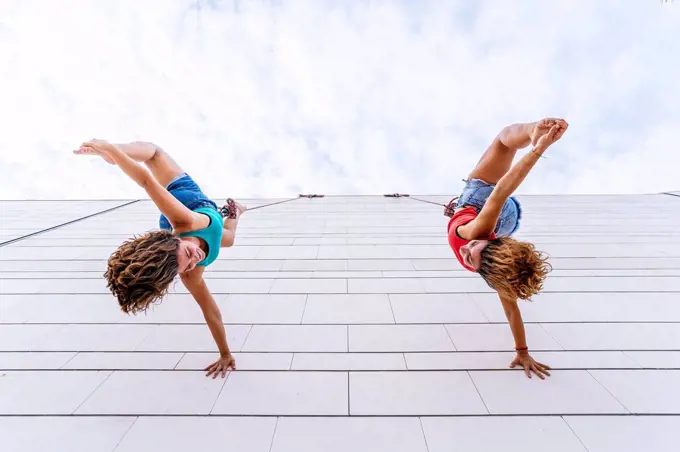 Aerial dancers touching toes while hanging on window