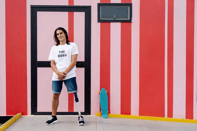 Man smiling while standing against multi colored wall