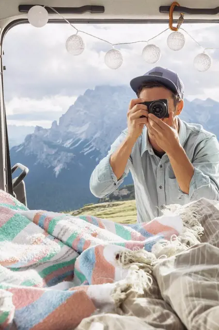 Male tourist photographing interior of campervan against mountains, Sesto Dolomites, Dolomites, Alto Adige, Italy