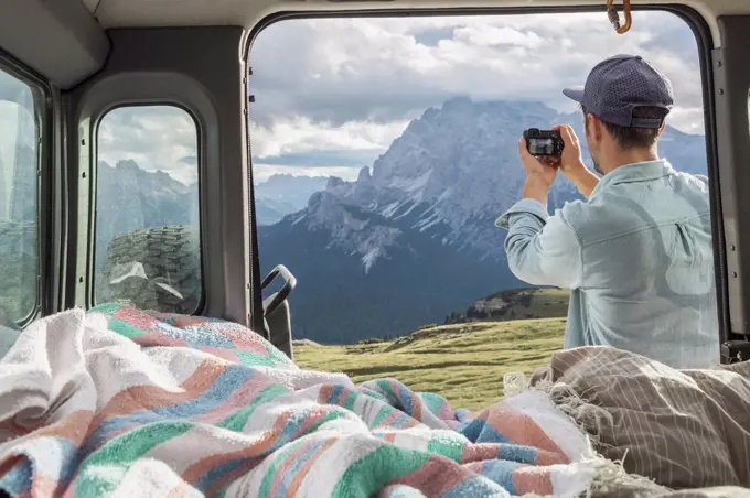 Man photographing scenic mountain ranges while standing by campervan. Sesto Dolomites, Dolomites, Alto Adige, Italy