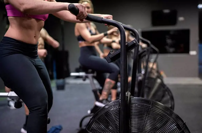 Athletes exercising on fitness bike in gym