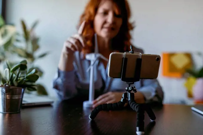 Woman making vlog on mobile phone while sitting at home