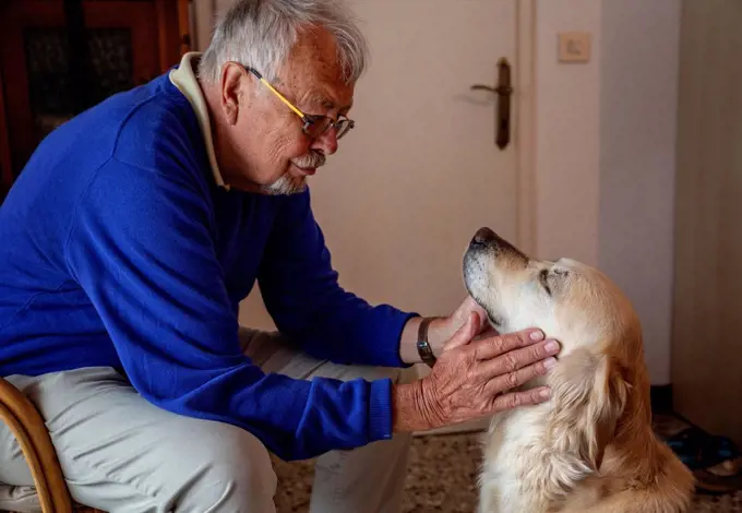 Senior man with dog sitting at home