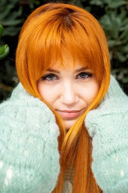 Beautiful woman with hand in hair against tree