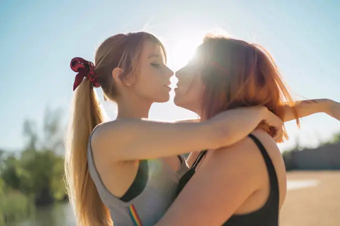 Lesbian couple doing romance while standing against sky