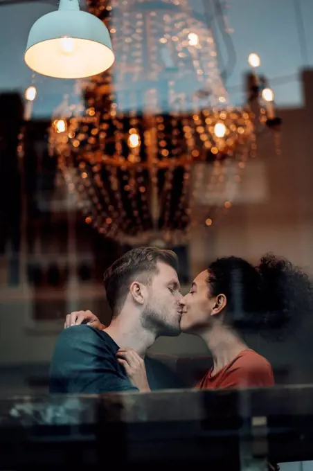 Boyfriend and girlfriend kissing each other while sitting at cafe