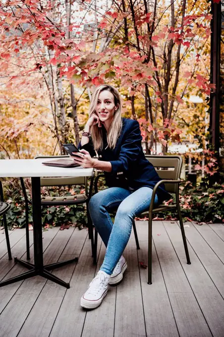 Beautiful woman looking away while sitting at terrace during autumn