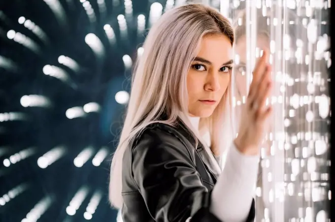 Attractive woman leaning on illuminated glass wall