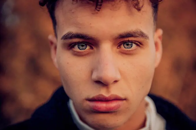 Young man with blue eyes in autumn forest