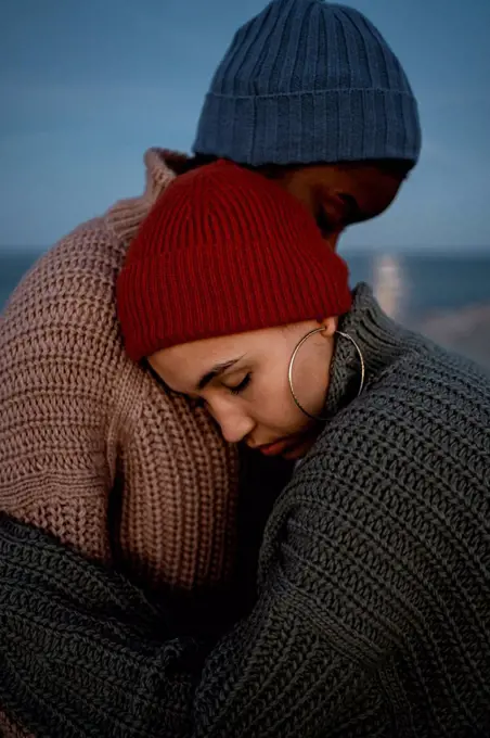 Young woman embracing friend while standing outdoors