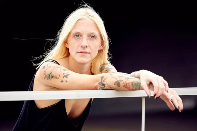 Young woman with blond hair looking away while leaning on railing