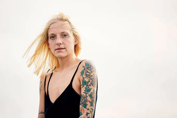 Tattooed young woman against clear sky