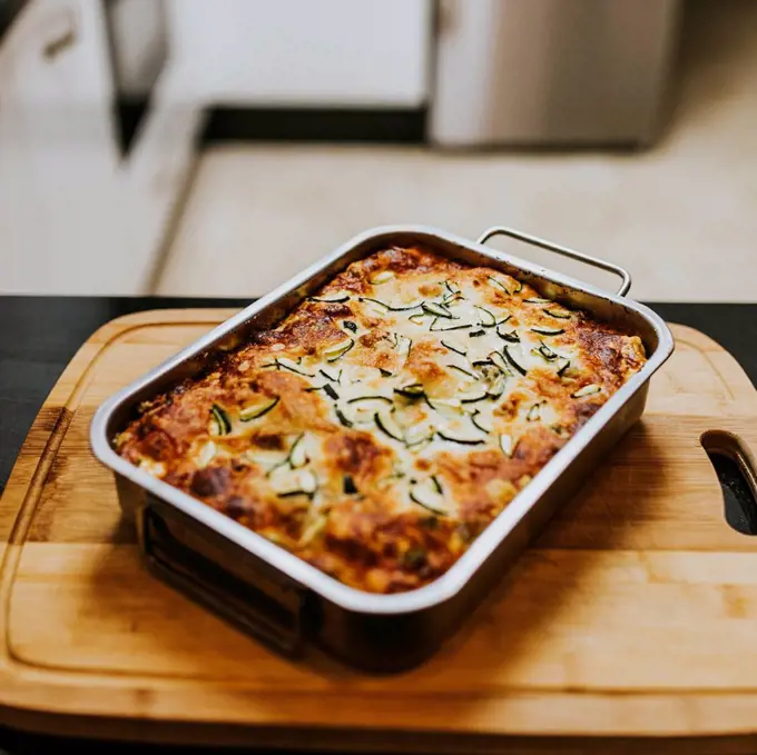 Homemade cooked lasagna with zucchini in tray on cutting board at home