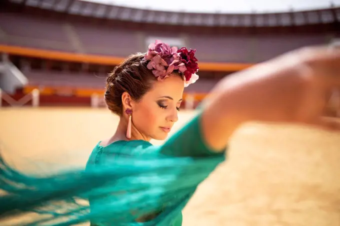 Close-up of flamenco dancer wearing flowers with eyes closed dancing in bullring