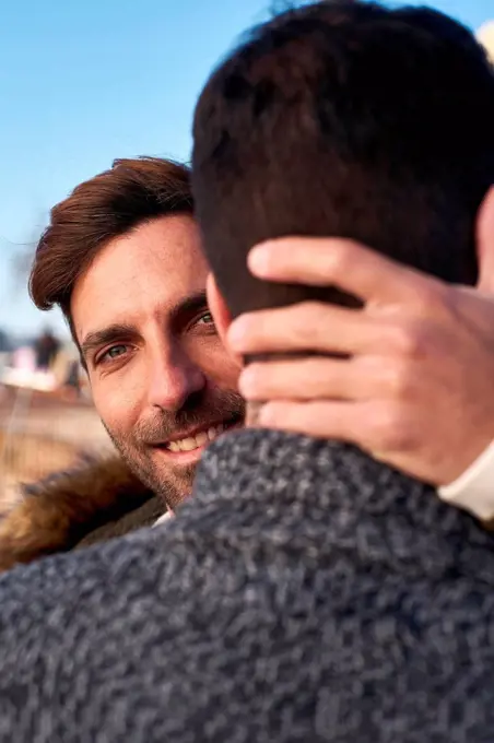 Close-up of smiling man embracing boyfriend