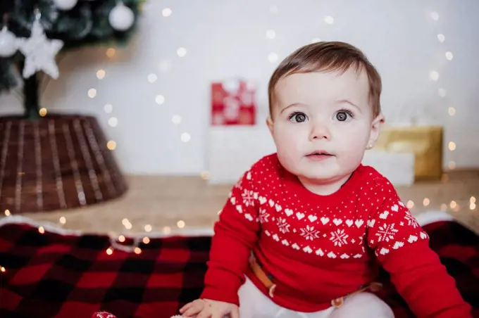 Cute baby girl staring while sitting at home during Christmas