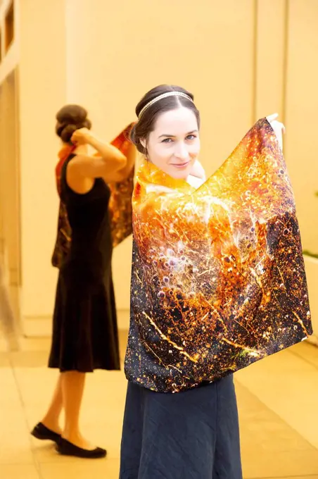 Smiling woman showing printed Chakra 3 on silk cloth while standing against mirror