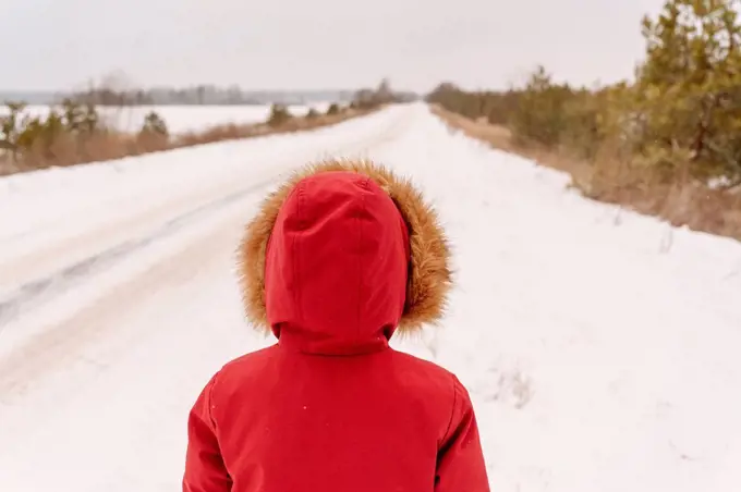 Boy wearing red winter coat standing on snowy landscape