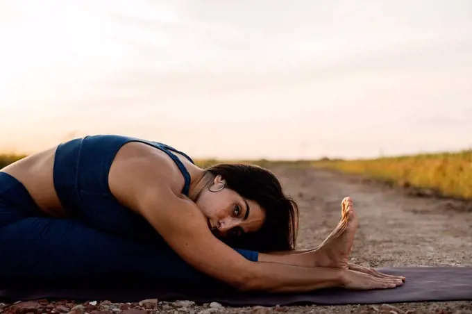 Woman practicing Paschimottasana on road