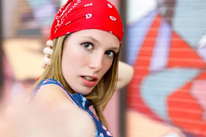 Beautiful young woman wearing bandana while standing by colorful shutter