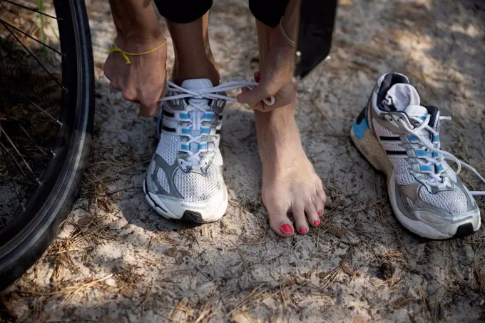 Female athlete tying sports shoelace by tire