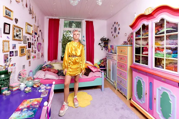 Beautiful woman wearing yellow dress in flashy bedroom at home