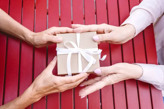 Woman giving gift to female friend at table in restaurant