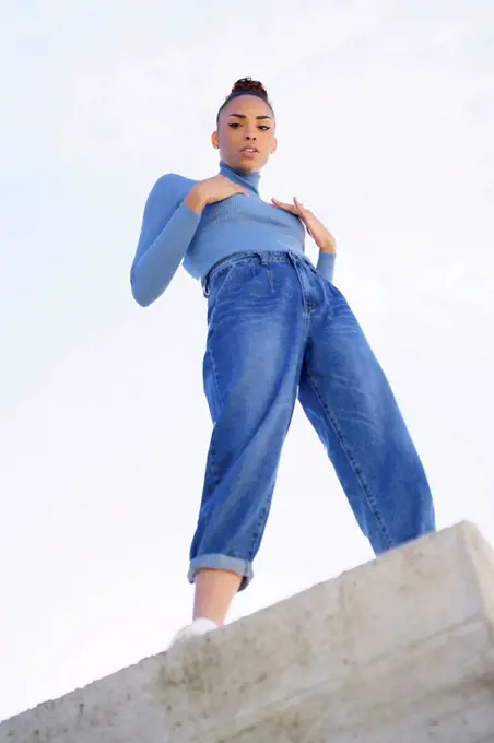 Young woman staring while standing on retaining wall