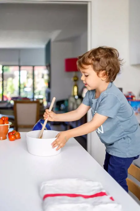 Cute boy cooking in kitchen at home