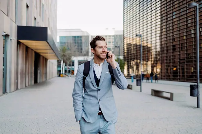 Businessman standing with hand in pocket talking on smart phone