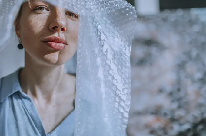 Female artist covered in bubble wrap at art studio