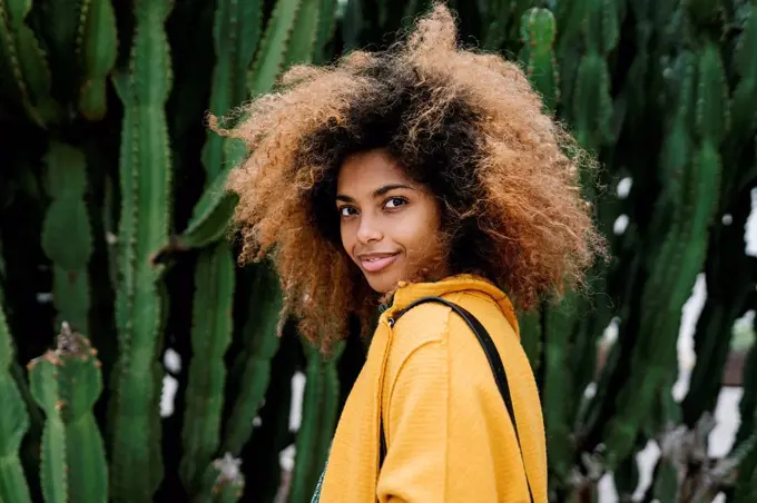 Smiling Afro woman standing by cactus in background