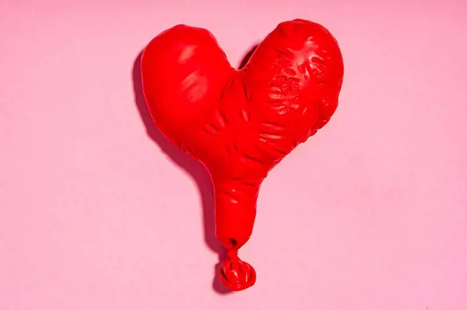 Studio shot of red heart shaped deflated balloon