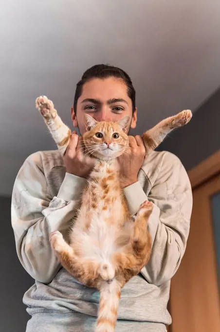 Young man playing with cat at home