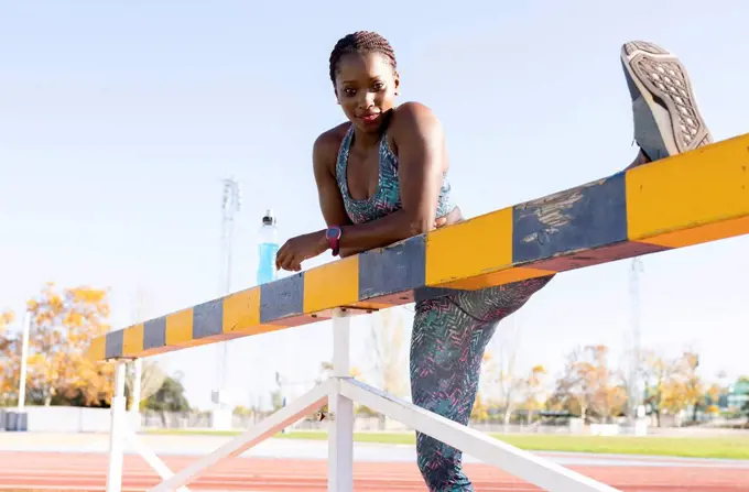 Female athlete with cool attitude stretching on balance beam during sunny day