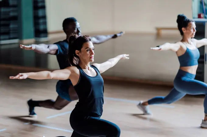 Female and male athlete friends in warrior position in gym