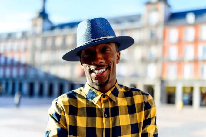 Smiling african man wearing hat while standing in city