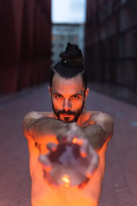 Man performing with acrylic ball on footpath at dusk