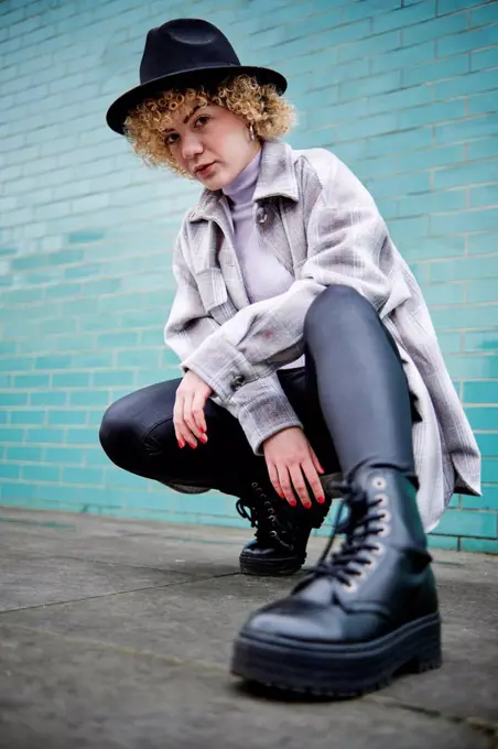 Woman in hat squatting on footpath