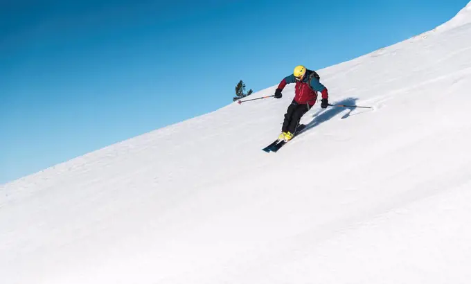 Mature man skiing on mountain slope against sky