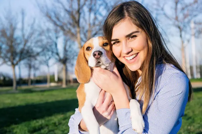 Female pet owner smiling while embracing dog at park